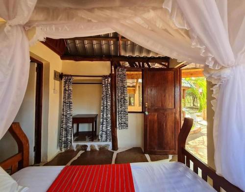 迪亚尼海滩Kijani Cottages - In Diani的一间卧室配有天蓬床和沙发