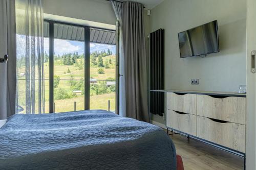 亚布卢尼齐亚Котеджі Лісові Форелі的一间卧室设有一张床和一个大窗户