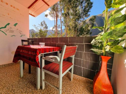 乌鲁班巴Valle verde, Hostel & camping的阳台配有桌椅、桌子和花瓶
