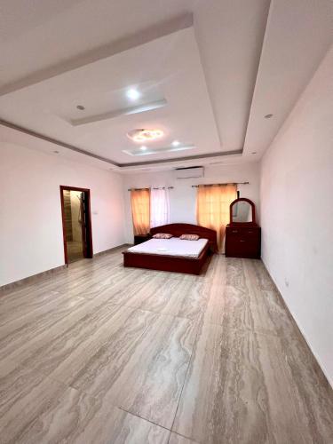 科托努Luxe Villa的一间卧室配有一张床,铺有木地板