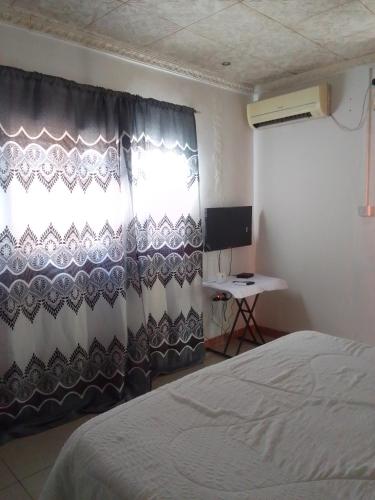 马翁Maun self catering accommodation的一间卧室配有一张床、一个窗口和一张书桌