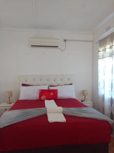 马翁Maun self catering accommodation的一间卧室配有红色的床和2条毛巾