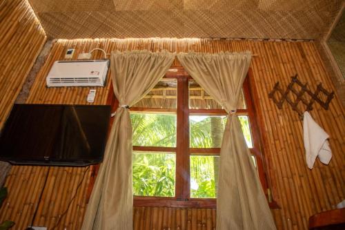 杜马格特Dumaguete Oasis Treehouse的客房设有带窗帘的窗户和电视。