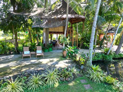 杜马格特Dumaguete Oasis Treehouse的一个带两把椅子的庭院和一座棕榈树房子