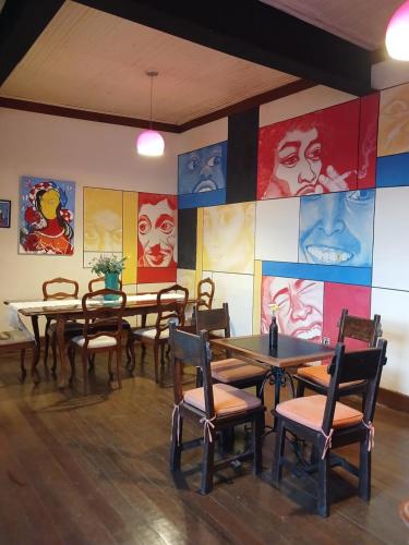 欧鲁普雷图Brumas Ouro Preto Hostel e Pousada的餐厅设有桌椅,墙上挂有绘画作品