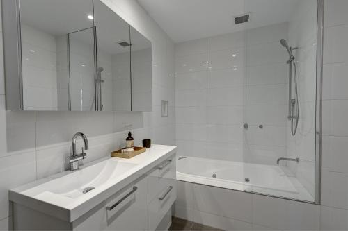墨尔本坎伯韦尔服务公寓式酒店的白色的浴室设有浴缸、水槽和淋浴。