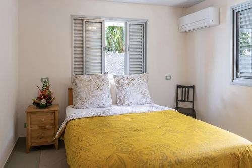 波拉波拉PARADISE的一间卧室配有一张黄色棉被和两个窗户。