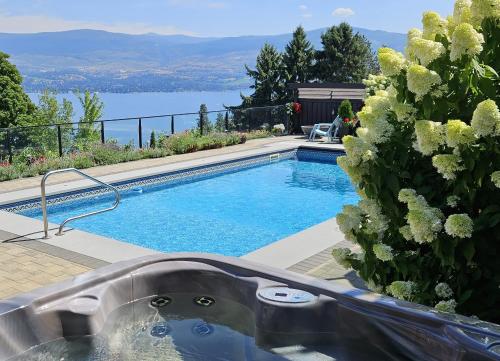 西基隆拿Stunning Lake View w Private Hot tub, Pool -snl & Outdoor Kitchen 2400sqft的一座游泳池,旁边设有浴缸,靠近一些花卉