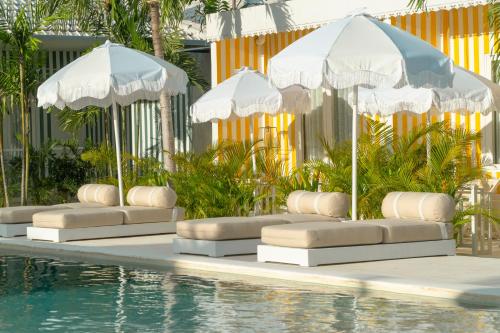 乌鲁瓦图Ria Uluwatu, Tropical Chic Hotel的一组遮阳伞,坐在游泳池旁