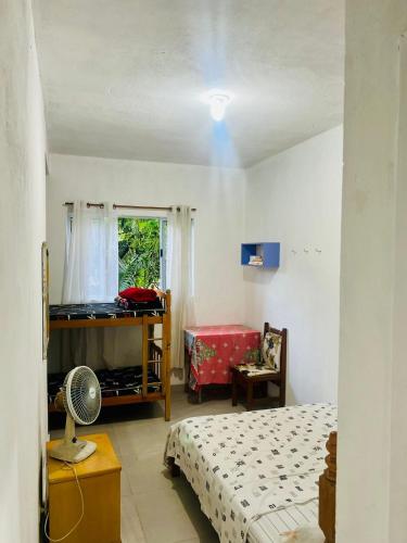 大普拉亚Xixova Hostel Japui são Vicente的一间卧室设有两张床和一个带风扇的窗户。