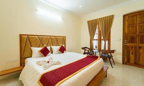 蓬蒂切里FabHotel Prime AR Phalazzo Resort的一间卧室配有一张床、一张桌子和一个窗户。