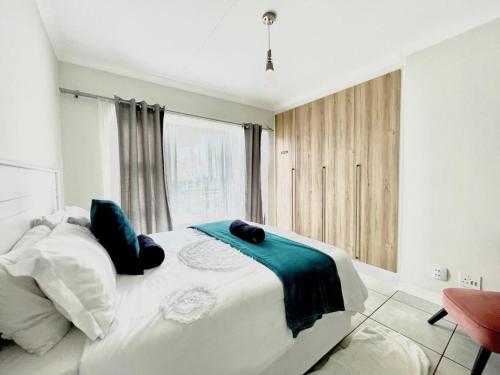 比勒陀利亚TK’s Penthouse - The Blyde的卧室配有带蓝色枕头的大型白色床