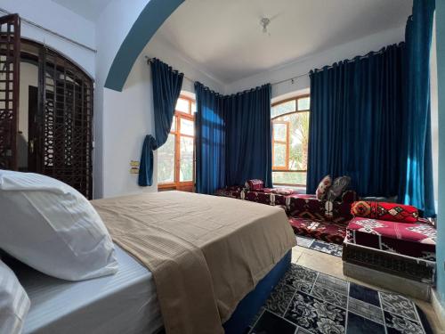 Al Mazghūnahpyramids view Guest villa的一间卧室配有蓝色窗帘、一张床和一张沙发