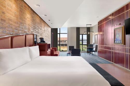 约翰内斯堡非洲梅尔罗斯普赖德阿彻傲途格精选酒店的一间卧室设有一张大床和砖墙