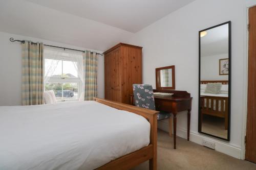 波特里斯Incline Cottage的一间卧室配有一张床、一张书桌和一面镜子