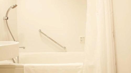大阪Shin-Osaka Station Hotel的白色的浴室设有浴缸和淋浴帘
