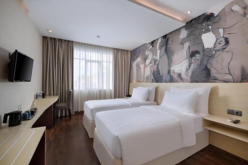 沙努尔Four Star by Trans Hotel的酒店客房设有两张床,墙上挂有绘画作品