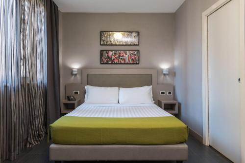 罗马Noba Hotel e Residenze的一间卧室配有一张带绿色和白色毯子的床