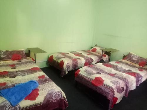 加德满都Om Kedareshwar Boys Hostel的一间房间,设有三张床,上面有红玫瑰