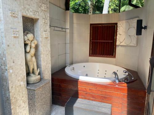 Paktako图斯塔康体度假村的一间带浴缸的浴室,配有2张雕像