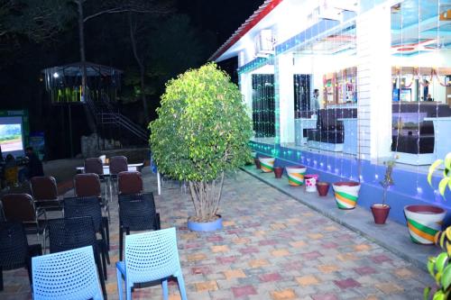 TigriShalini Batika & Eco Resort的一座建筑前的庭院,庭院里摆放着椅子和一棵树