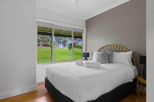 NabiacLake House Family Stay - Pool, Firepit, Games room的卧室设有一张白色大床和一扇窗户。