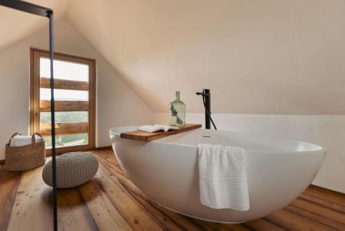 德意志兰茨贝格Am Wildbachberg - Luxus Ferienhäuser mit Infinitypool, Privatsauna und Weinkeller的带窗户的浴室内的白色浴缸