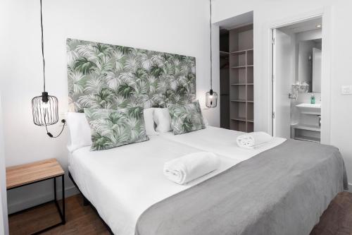 格拉纳达Apartamentos de Isabella的一间卧室配有一张带热带床头板的大型白色床