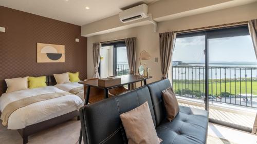 GushiホテルエアポートビューNAHA的一间带一张床和一张书桌的卧室以及一个阳台