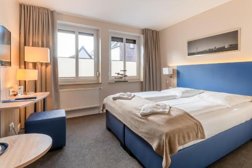 胡苏姆Nordsee-Hotel Hinrichsen的一间卧室配有一张大床和一张桌子