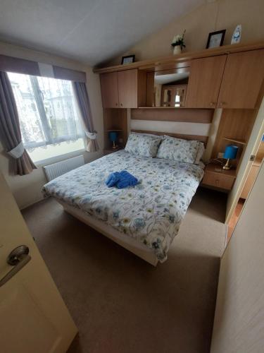 新米尔顿Seaside caravan Hoburne Naish Holiday Park Naish Common 83的一间卧室,床上有蓝色衬衫
