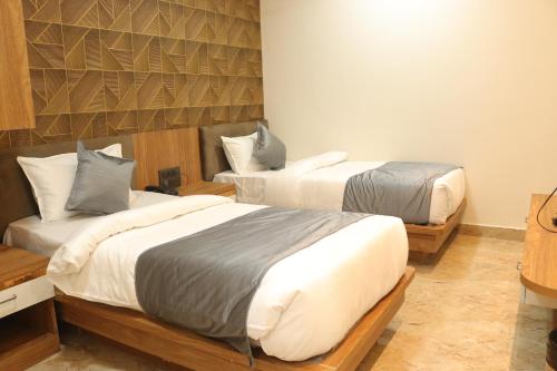 瓜廖尔Hotel maxsun gwalior的一间卧室设有两张床和一堵墙