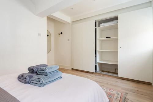 伦敦2BD Mews House, Wanstead的一间白色卧室,床上配有毛巾,卧室设有一个开放式衣柜