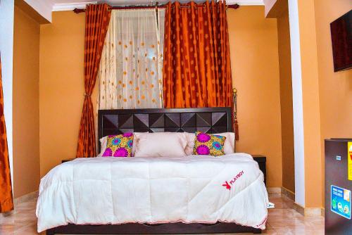 塔科拉迪Thy favour hotel的一间卧室配有带白色床单和色彩缤纷的枕头的床。