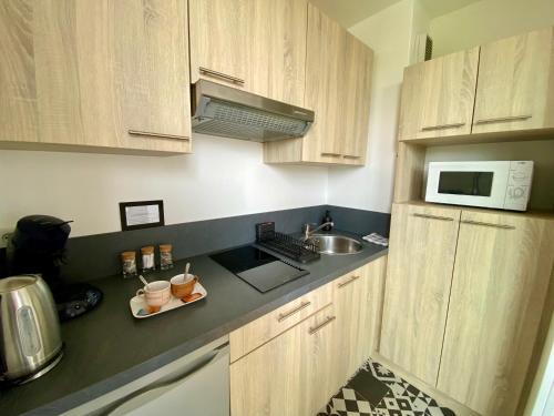 雷恩Superbe appartement confortable, proche centre ville的厨房配有木制橱柜、水槽和微波炉