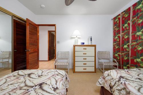 科纳Kahaluu Bay Villas 304的一间卧室配有一张床、梳妆台和椅子