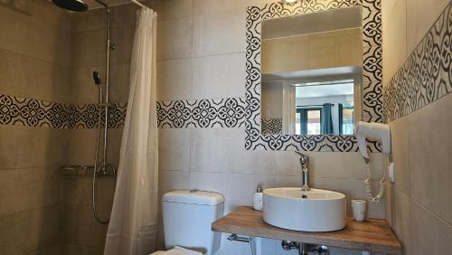 圣加利尼Akteon Rooms的一间带水槽、镜子和卫生间的浴室