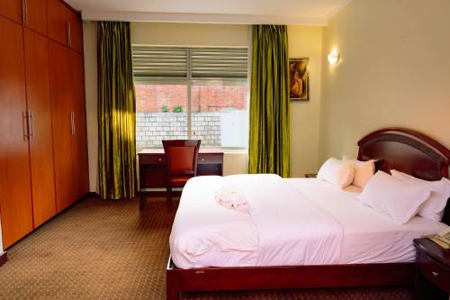 基加利Nobilis Hotel and Apartments的卧室配有白色的床、书桌和窗户。