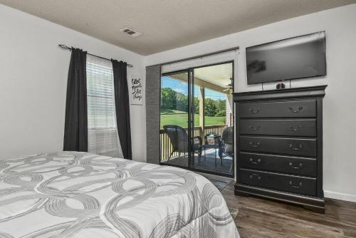布兰森Table Rock Escape at Pointe Royale的一间卧室配有一张床和一个带平面电视的梳妆台。