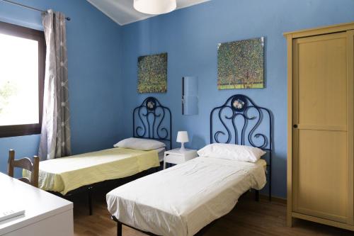 MontefanoVilla Maia - Homelike Villas的蓝色墙壁客房的两张床