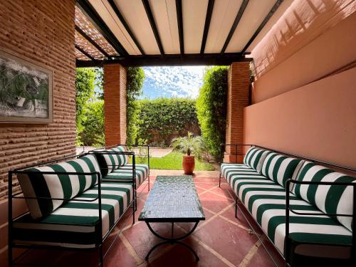 马拉喀什Villa Sofia - Golf Amelkis Marrakech的天井上配有长沙发和桌子的门廊