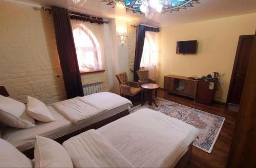 撒马尔罕KAMILA Hotel Boutique的客房设有两张床、一张桌子和一台电视机。