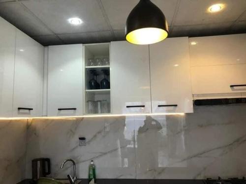 科托努Villa trois chambres avec piscine的厨房配有白色橱柜和台面上的灯