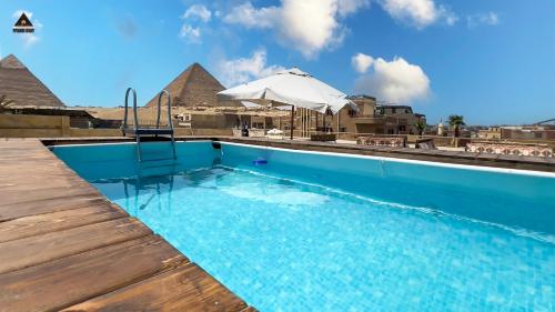 开罗Pyramids Height Hotel & Pyramids Master Scene Rooftop的一个带遮阳伞和金字塔的游泳池