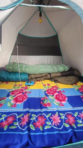 KedārnāthNamasteNomads X Musafirokibasti的帐篷内的一张床位,上面有毯子