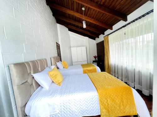 基多Gaby’s Home.的一间卧室配有两张带黄色枕头的床