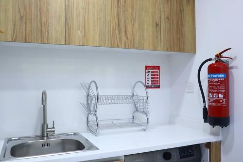 阿布扎比MasdarCity Bliss 2BR apartment的厨房柜台设有水槽和灭火器