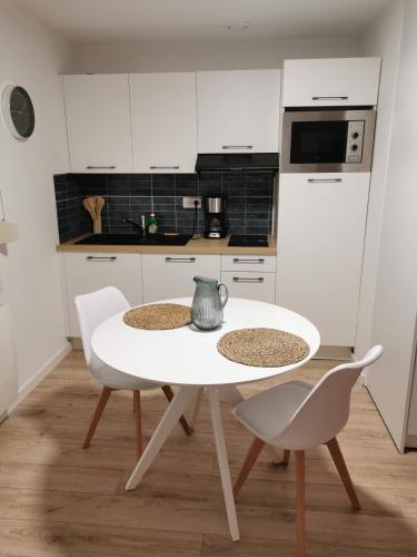 岩尼维利Studio Casa Amnéville的白色的厨房配有白色的桌子和椅子