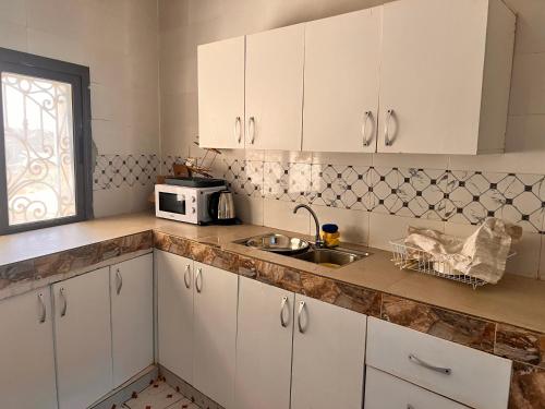 达喀尔LUXE Studio的厨房配有白色橱柜、水槽和微波炉