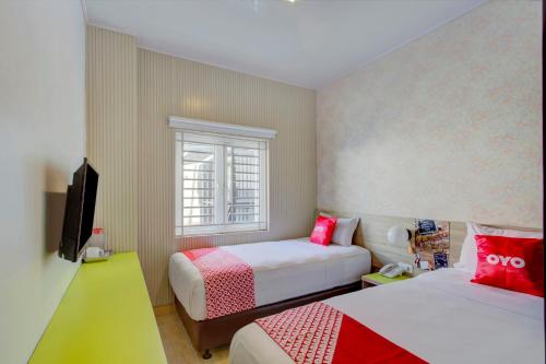 雅加达Super OYO 4005 Bunga Dahlia Guest House的一间卧室设有两张床和窗户。